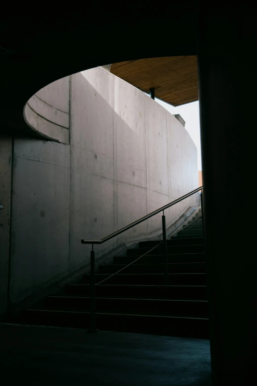 a man riding a skateboard down a flight of stairs, inspired by Tadao Ando, unsplash, brutalism, wall darkness, high quality photo, gray concrete, view from inside