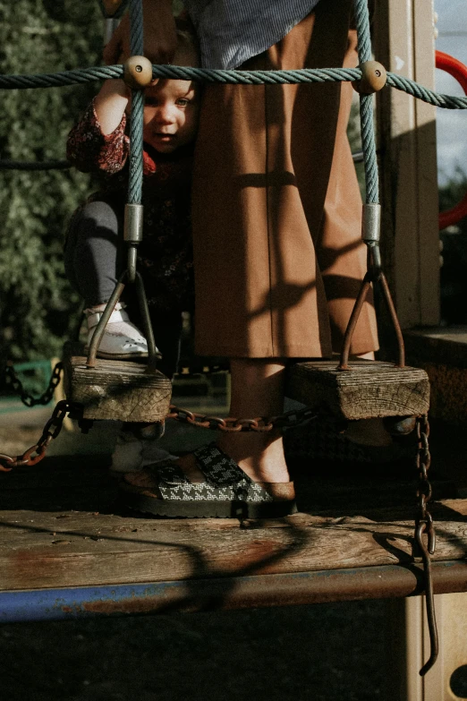 a woman standing on top of a wooden platform, by Elsa Bleda, trending on pexels, realism, donkey riding a playground swing, focus on sneakers only, muted browns, ((chains))