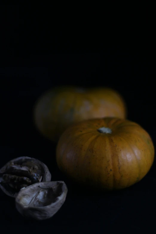 a couple of pumpkins sitting on top of a table, a still life, by Yasushi Sugiyama, unsplash, purism, in front of a black background, walnuts, viewed from the side, ansel ]
