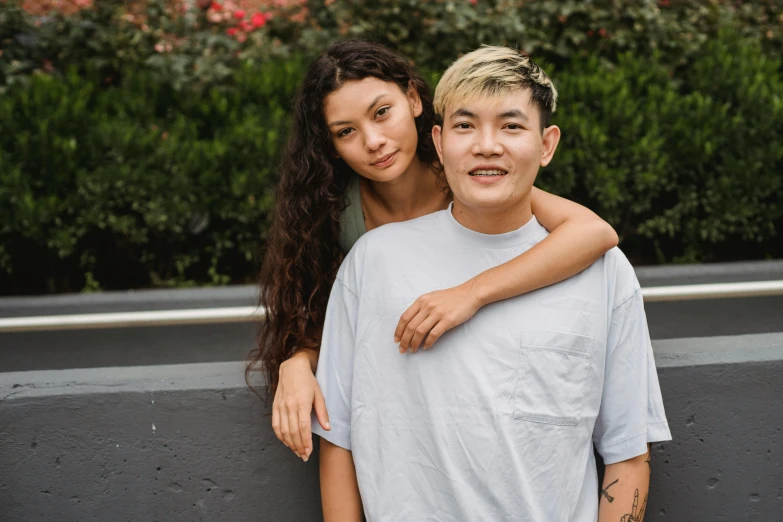 a man and a woman standing next to each other, trending on pexels, half asian, lesbian, diverse haircuts, 18 years old