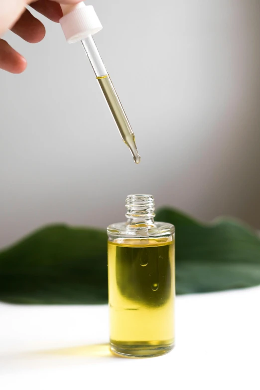 a close up of a bottle of oil with a dropper, inspired by Ceferí Olivé, unsplash, partially cupping her hands, on white background, thumbnail, thc