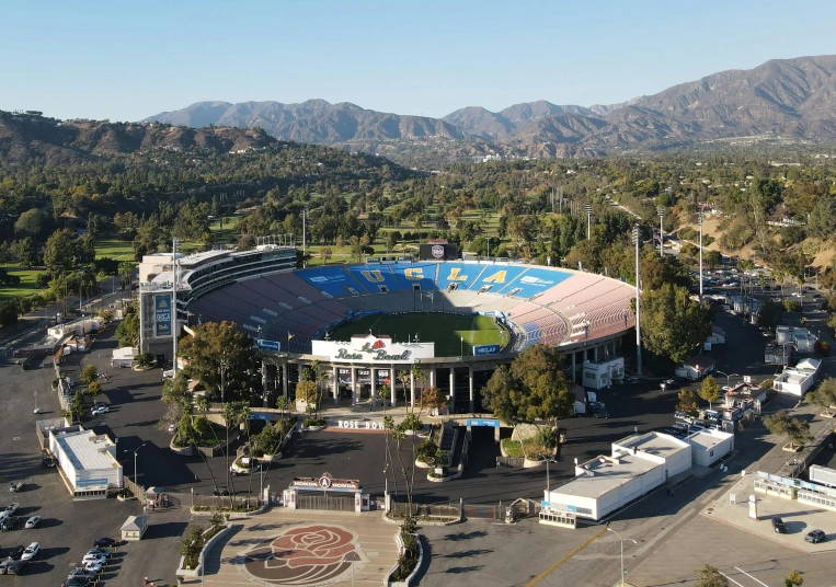 an aerial view of a football stadium with mountains in the background, a photo, hollywood promotional image, a park, sunken, 2022 photograph