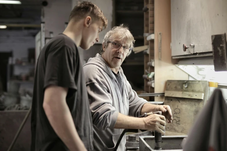 a couple of men standing next to each other in a kitchen, arbeitsrat für kunst, steel plating, school class, focused photo, teaching