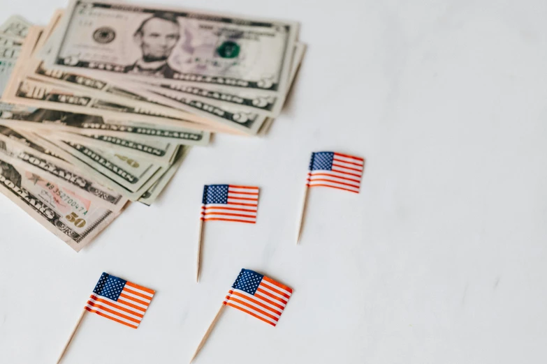 small american flags sitting on top of a pile of money, a portrait, trending on unsplash, on a white table, 🦩🪐🐞👩🏻🦳, miniature product photo, instagram photo