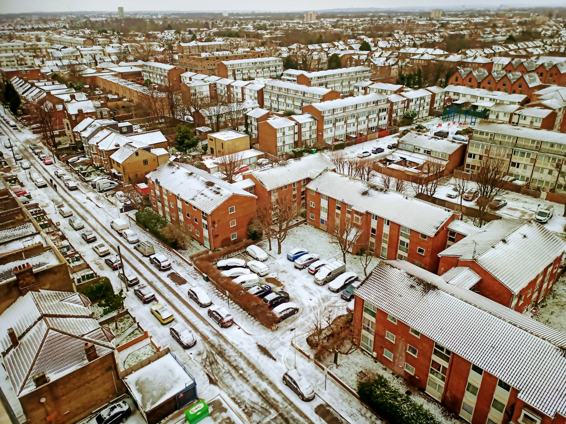 a city filled with lots of snow covered buildings, a photo, inspired by Thomas Struth, unsplash, elstree, wide high angle view, square, residential area