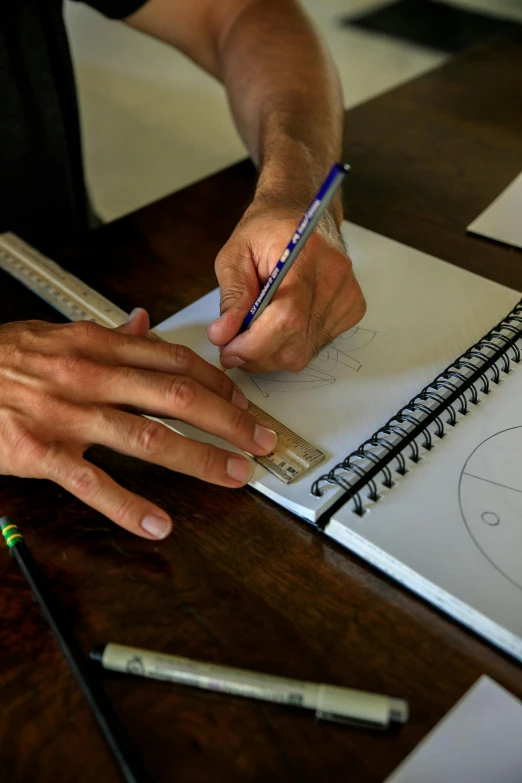 a man is drawing on a piece of paper, by Joe Stefanelli, golden ratio jewelry lights, letterboxing, circular, writing in journal