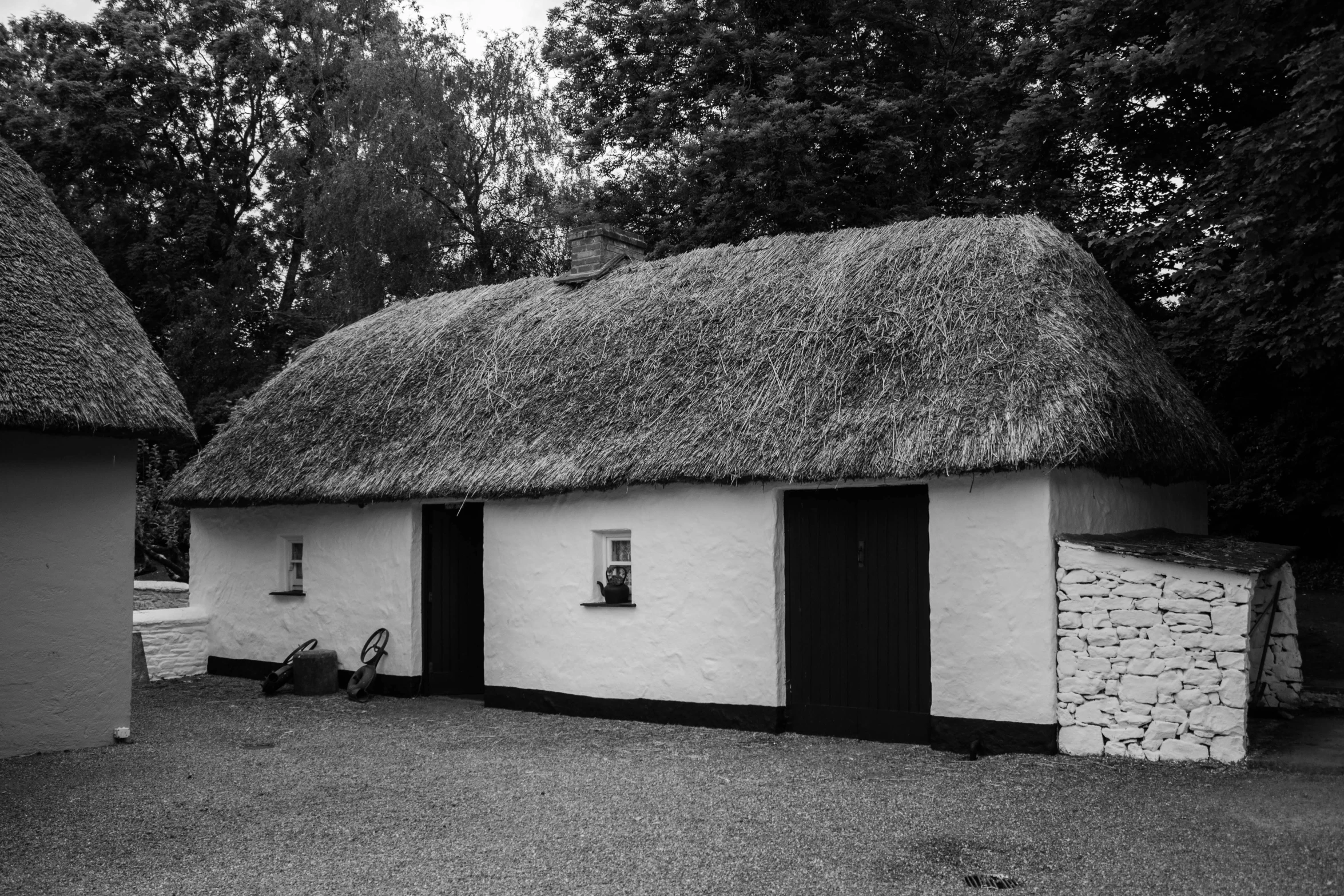 a black and white photo of a thatched house, by Kevin Connor, pexels contest winner, folk art, mayo, promo image, white building, front and side view