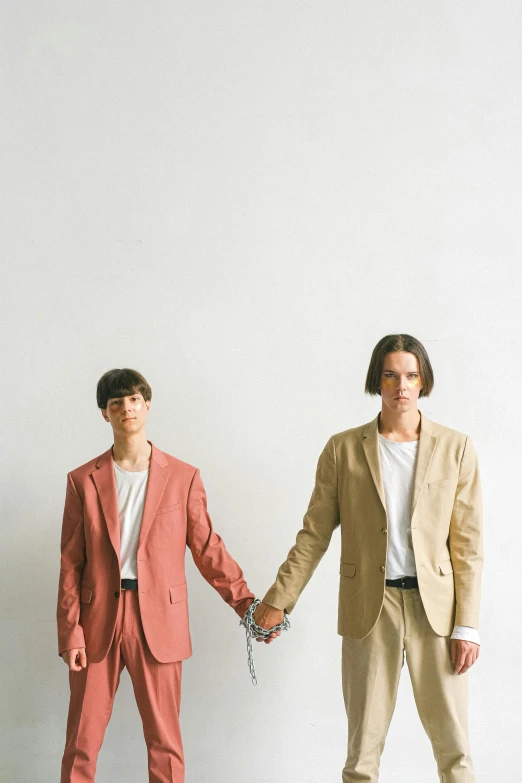 two men standing next to each other holding hands, an album cover, unsplash, bauhaus, tan suit, yuya nagai, lesbians, linen