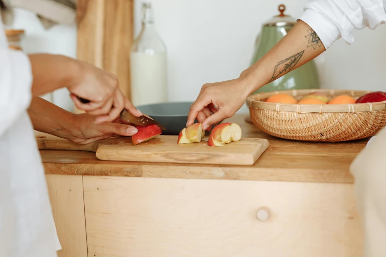 two people cutting apples on a cutting board, by Niko Henrichon, small kitchen, brown, natural wood top, without duplicate image