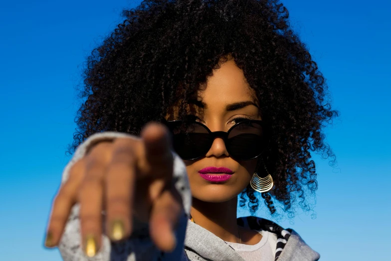 a close up of a person pointing a finger at the camera, an album cover, pexels, natural hair, implanted sunglasses, young lady, ankh