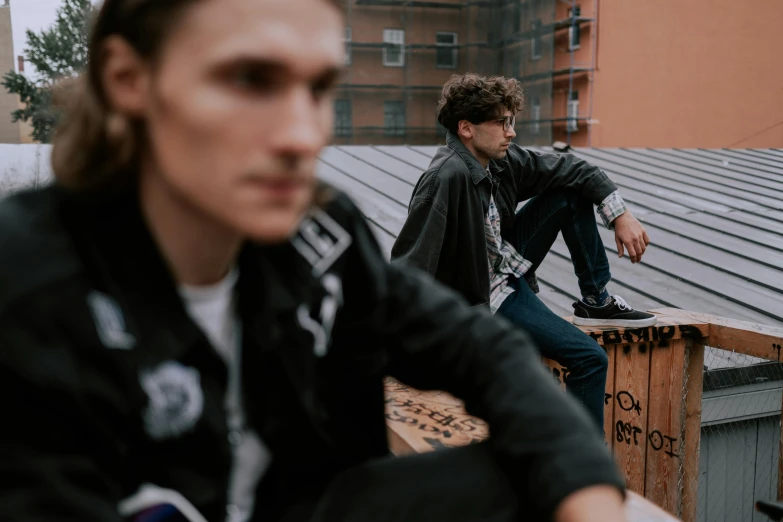 a couple of men sitting on top of a roof, a picture, by Emma Andijewska, trending on pexels, black bomber jacket, band promo, wearing adidas clothing, high detailed