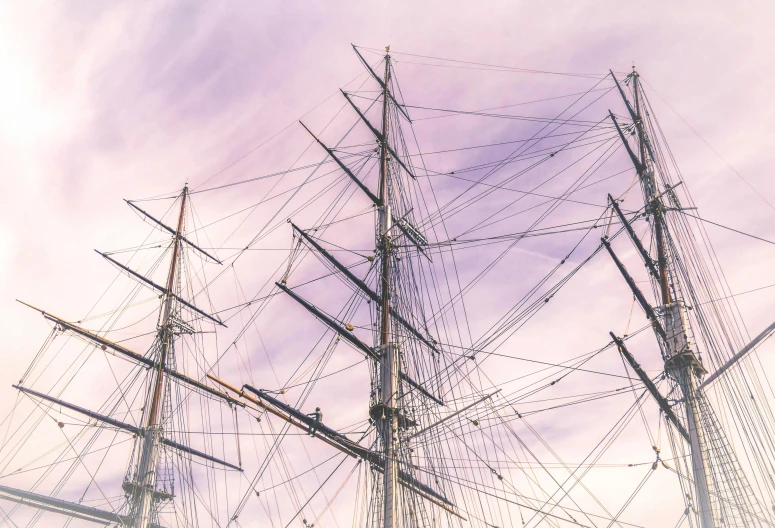 a tall ship sitting on top of a body of water, an album cover, pexels contest winner, romanticism, the sky is pink, shipyard, three masts, 3/4 view from below