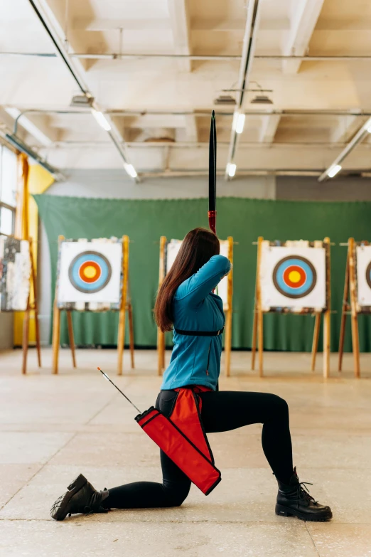 a woman is practicing archery in a target room, pexels contest winner, arabesque, kneeling, local gym, rectangle