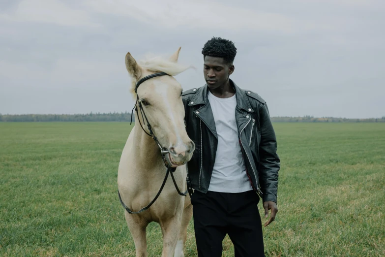 a man standing next to a horse in a field, an album cover, trending on pexels, black skin, non binary model, movie still 8 k, performing a music video