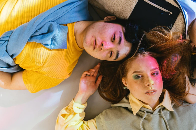 a group of people laying on top of each other, an album cover, by Julia Pishtar, brunette boy and redhead boy, yellow clothes, lee madgwick & liam wong, laying on her back on a bed