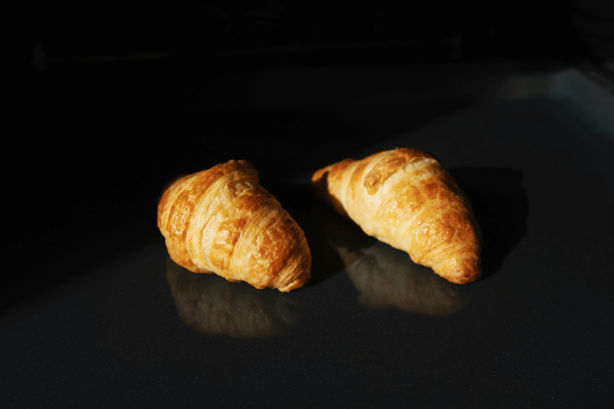 a couple of croissants sitting on top of a table, in front of a black background, high quality product image”, panels, très détaillé