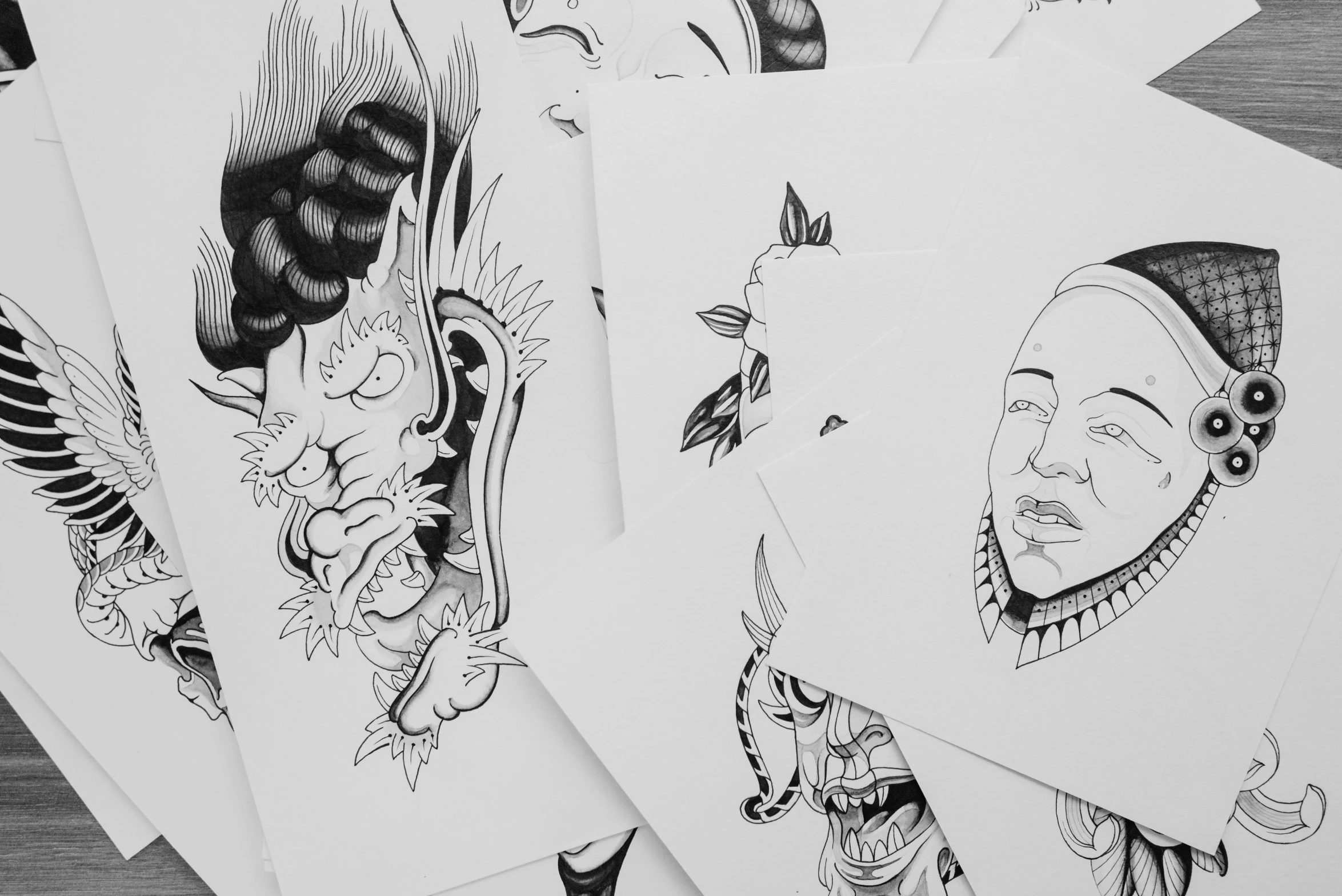 a bunch of tattoos sitting on top of a wooden table, an ink drawing, by Adam Rex, face line drawing, close up shots, shikishi, behance art