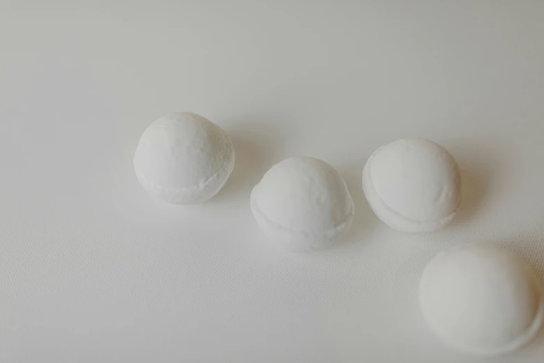 a group of white balls sitting on top of a white surface, product image, candy treatments, less detailing, foamy bubbles