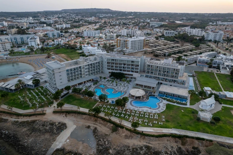 a large building next to a body of water, cyprus, hotel room, high view, white wall complex