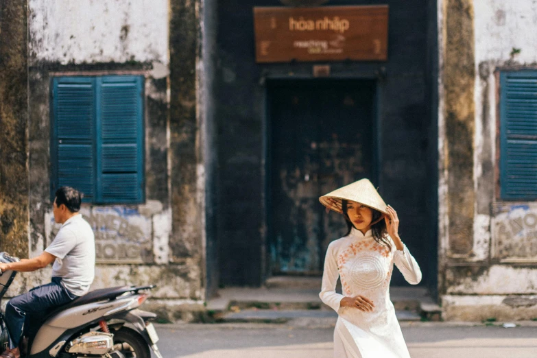 a woman in a white dress walking down a street, a photo, inspired by Ruth Jên, trending on unsplash, ao dai, pith helmet, square, brocade robes