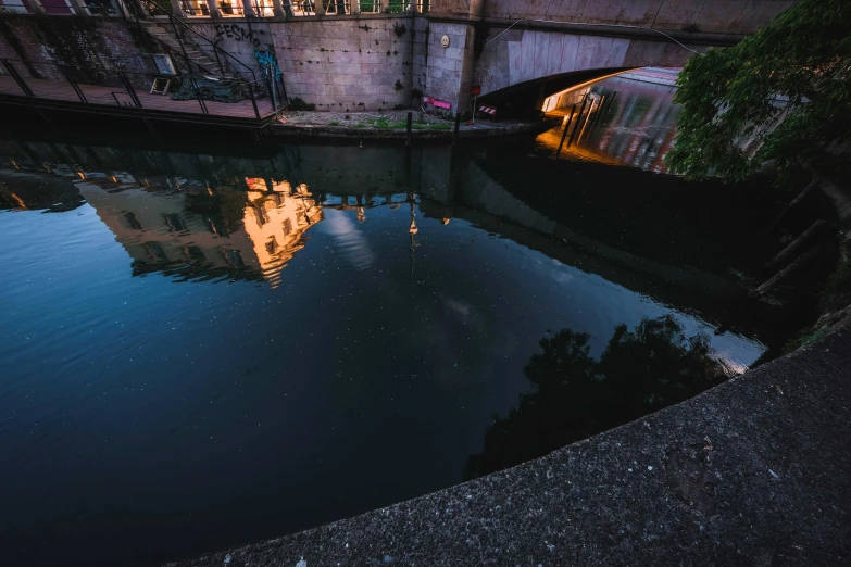 a bridge over a body of water with a building in the background, inspired by Elsa Bleda, unsplash contest winner, dark wet london alley at night, reflections. shady, late summer evening, paul davey