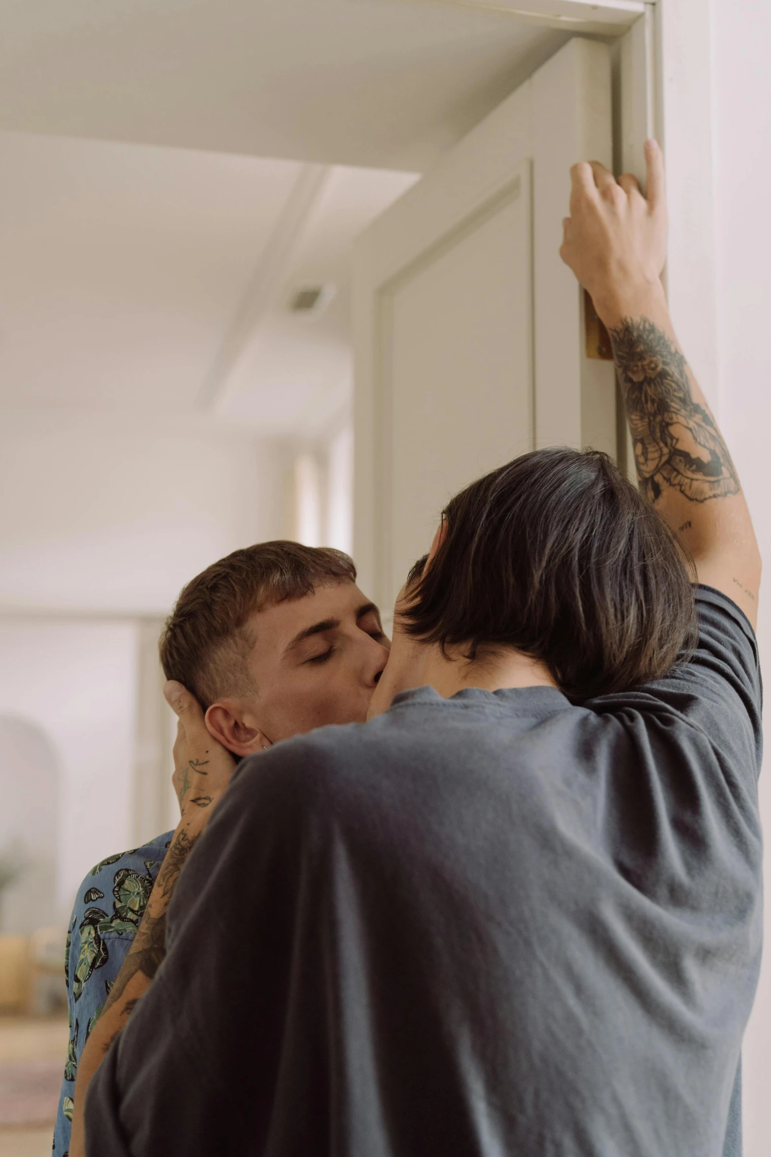 a man giving a woman a kiss on the cheek, a tattoo, by Jessie Alexandra Dick, trending on pexels, hung above the door, vhs footage still, non binary model, two men hugging