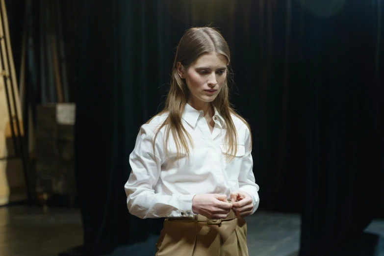 a woman in a white shirt and tan skirt, by Nina Hamnett, trending on unsplash, renaissance, production photo, with a sad expression, collared shirt, ( ( theatrical ) )