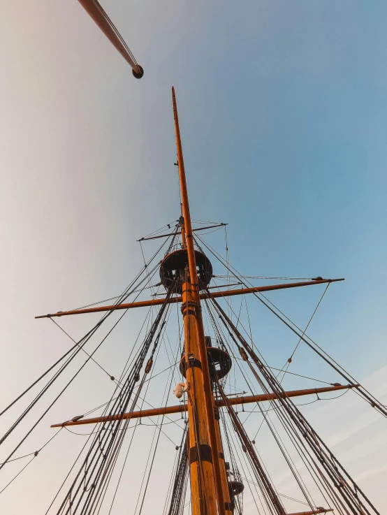 a tall ship sitting on top of a body of water, looking at the sky, low quality photo, mid view from below her feet, 2019 trending photo