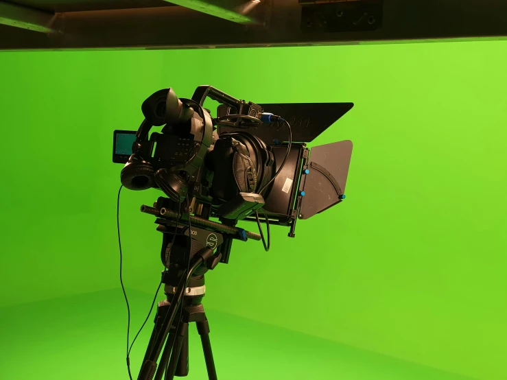 a camera on a tripod in front of a green screen, a raytraced image, video art, theatre equipment, volumetric lighting - h 7 6 8, looking towards camera, set photograph