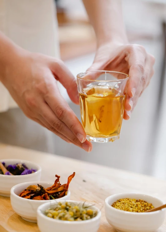 a close up of a person holding a glass of tea, process art, ingredients on the table, curated collection, acupuncture treatment, full product shot