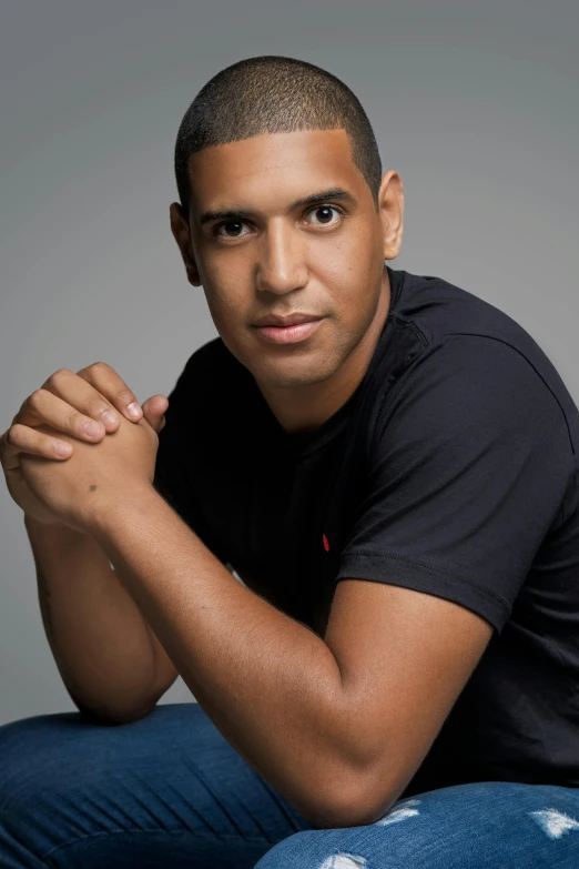 a man in a black shirt and jeans posing for a picture, inspired by Francis Souza, headshot photograph, cleanshaven!, press shot, brook