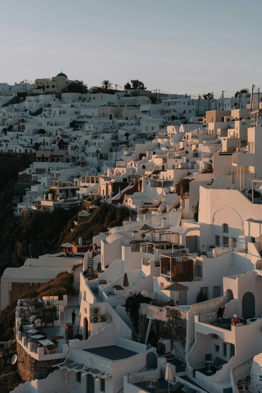 a view of a town from the top of a hill, trending on unsplash, neoclassicism, cycladic sculptural style, cliff side at dusk, low quality photo, white buildings