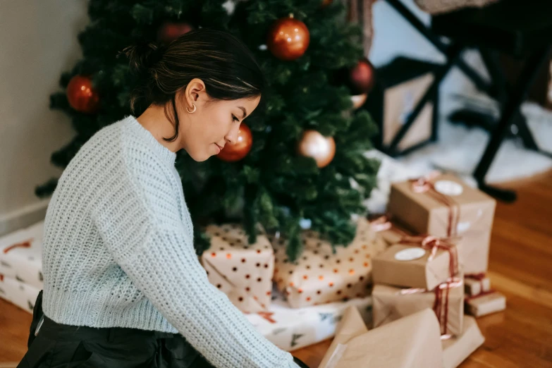 a woman sitting on the floor in front of a christmas tree, pexels contest winner, happening, manuka, profile image, cardboard, presenting wares