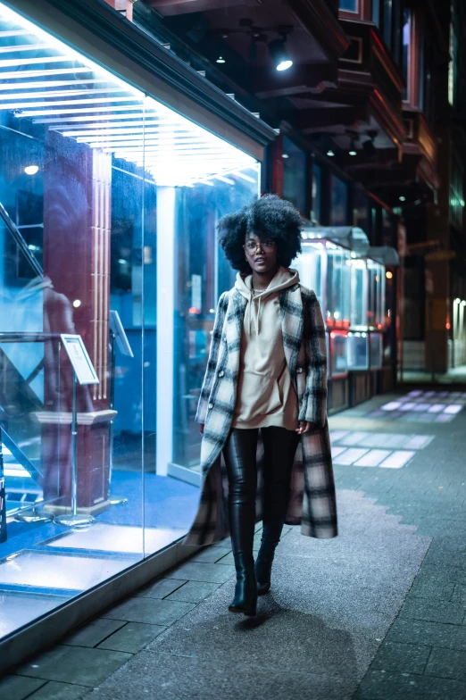 a woman standing in front of a store window, pexels contest winner, afrofuturism, wearing hunter coat, on a street at night, sza, style game square enix life