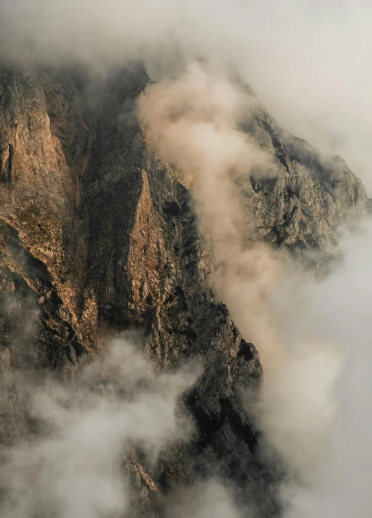 a plane flying over a mountain covered in clouds, an album cover, inspired by Kim Keever, pexels contest winner, rugged face, telephoto shot, cliffs, extreme panoramic