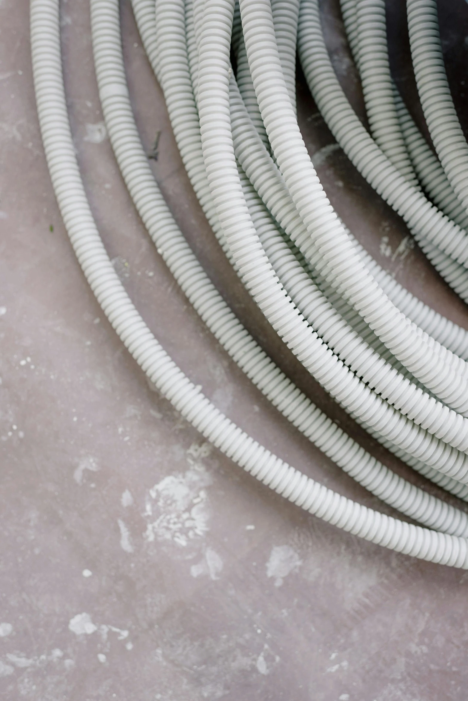 a white hose sitting on top of a cement floor, inspired by W. Lindsay Cable, trending on pexels, plasticien, electrical details, a pair of ribbed, detailed product image, zoomed in