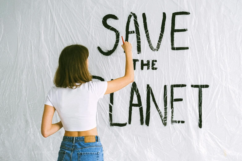 a woman writing save the planet on a wall, trending on pexels, avatar image, cloth banners, sydney sweeney, covered solar system