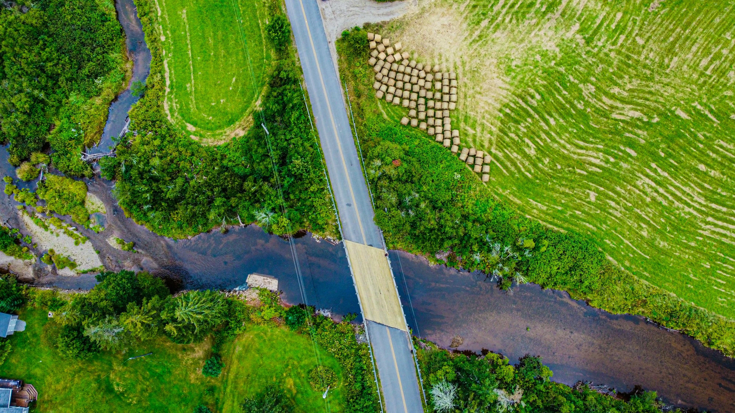 a river running through a lush green field, by Daniel Lieske, pexels contest winner, hurufiyya, bridges crossing the gap, top down perspecrive, thumbnail, roadside