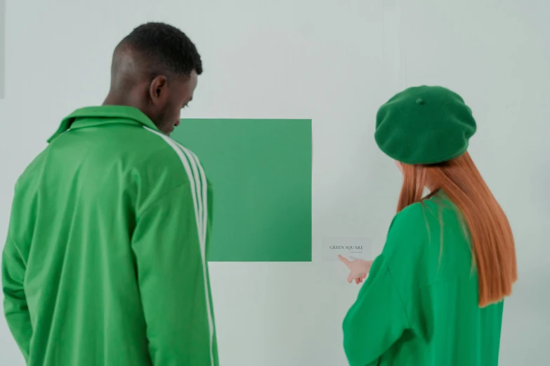 a man and a woman standing next to each other, a painting, inspired by Art Green, trending on pexels, interactive art, wearing green clothing, hidden message, single color, rectangle