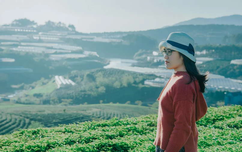 a woman standing on top of a lush green hillside, inspired by Ma Yuanyu, pexels contest winner, wearing teal beanie, secret tea society, [ cinematic, woman with rose tinted glasses