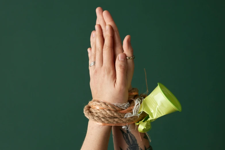 a woman's hands tied up with a rope, an album cover, inspired by Sarah Lucas, trending on pexels, hurufiyya, copper and emerald jewelry, the sacred cup of understading, hand gesture, green blessing