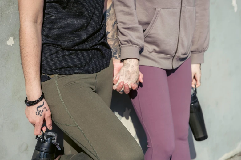 a couple of people standing next to each other, by Nina Hamnett, trending on pexels, leggings, lesbian embrace, natural hands and arms, prana