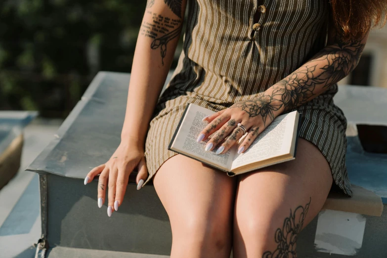 a woman sitting on a bench reading a book, a tattoo, trending on pexels, long nails, highly symmetric body parts, on a pedestal, yakuza tattoo on body
