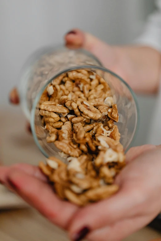 a person holding a bowl of nuts in their hands, a portrait, pexels, inside a beer glass, bottom body close up, 1 6 x 1 6, walnut wood