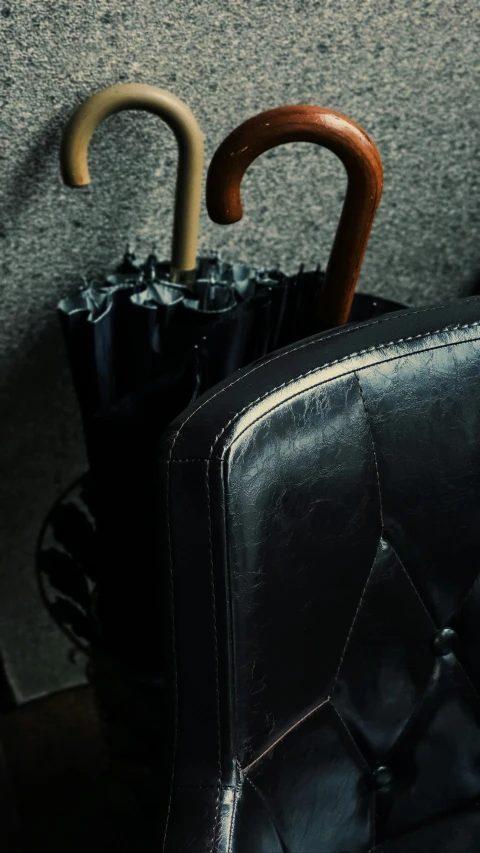 a pair of umbrellas sitting on top of a chair, an album cover, unsplash, black leather, highly detailed image, luggage, main colour - black