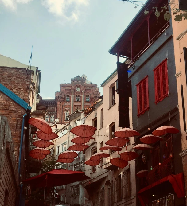 a group of umbrellas hanging from the side of a building, 'the red citadel, street lanterns, colour photo, city views