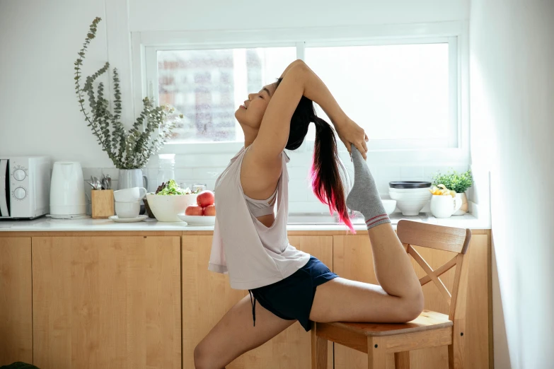 a woman doing a yoga pose in a kitchen, pexels contest winner, arabesque, long ponytail, asian female, sitting on chair, thigh focus