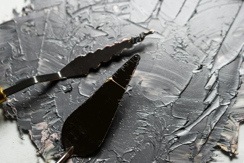 a knife, fork and knife rest on a piece of paper, an ultrafine detailed painting, inspired by Lucio Fontana, trending on pexels, abstract art, dark chocolate painting, silver palette, black resin, closeup - view