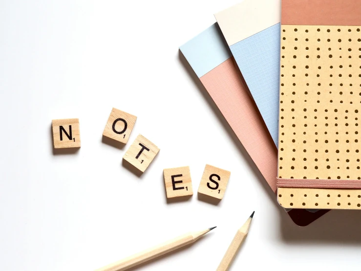 a note pad sitting on top of a table next to a pencil, trending on pexels, building blocks, background image, lettering, set against a white background