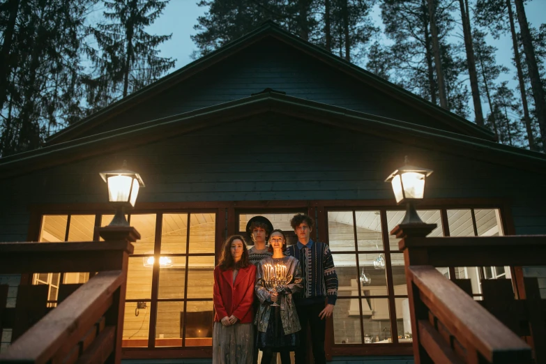 a group of people standing in front of a cabin, a portrait, by Jaakko Mattila, pexels contest winner, art nouveau, cozy candlelight, black fir, still from a wes anderson movie, in karuizawa